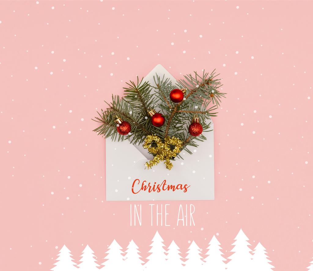 top view of white envelope with fir twigs and shiny christmas baubles isolated on pink with "christmas in the air" inspiration, snow and christmas trees illustration - Photo, Image