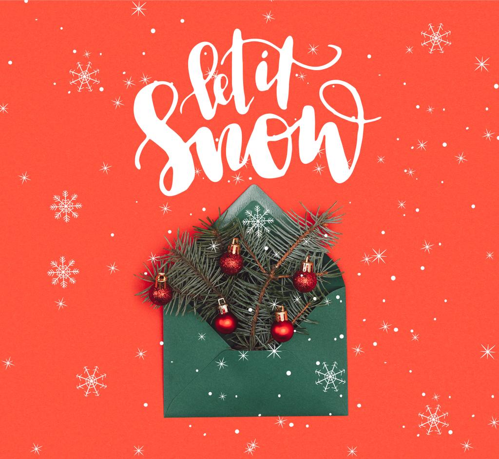 vista de cerca del sobre verde con ramitas de abeto y adornos de Navidad brillantes aislados en rojo con letras de "déjalo nevar" y copos de nieve
 - Foto, Imagen