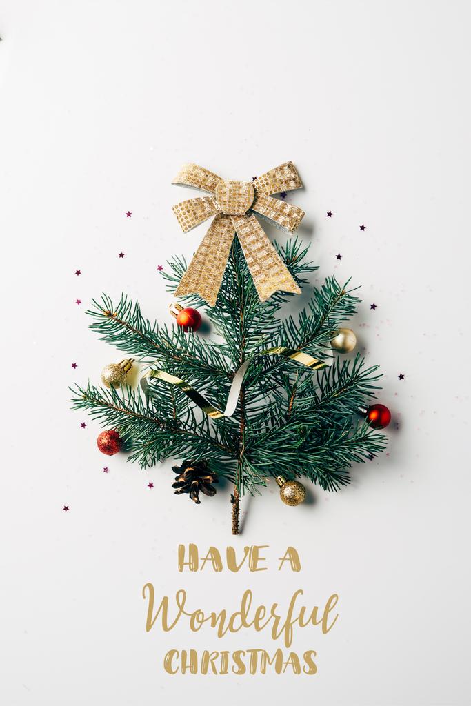 Blick von oben auf grünen Kiefernzweig, der als festlicher Weihnachtsbaum mit Schleife auf weißem Hintergrund mit der Inspiration "Have a wonderful christmas" geschmückt ist  - Foto, Bild