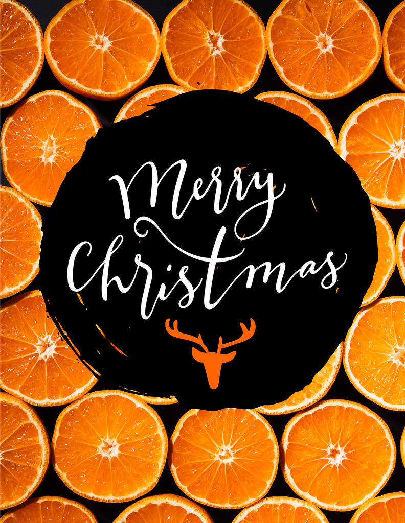 full frame of arranged cut tangerines halves on black background with "merry christmas" lettering with deer head - Photo, Image