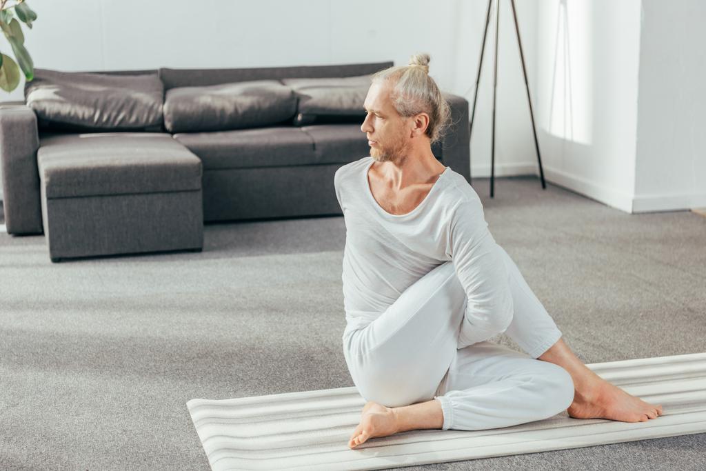 pohled z vysoké úhlu flexibilní koncentrované dospělého člověka cvičit jógu a koukal doma - Fotografie, Obrázek