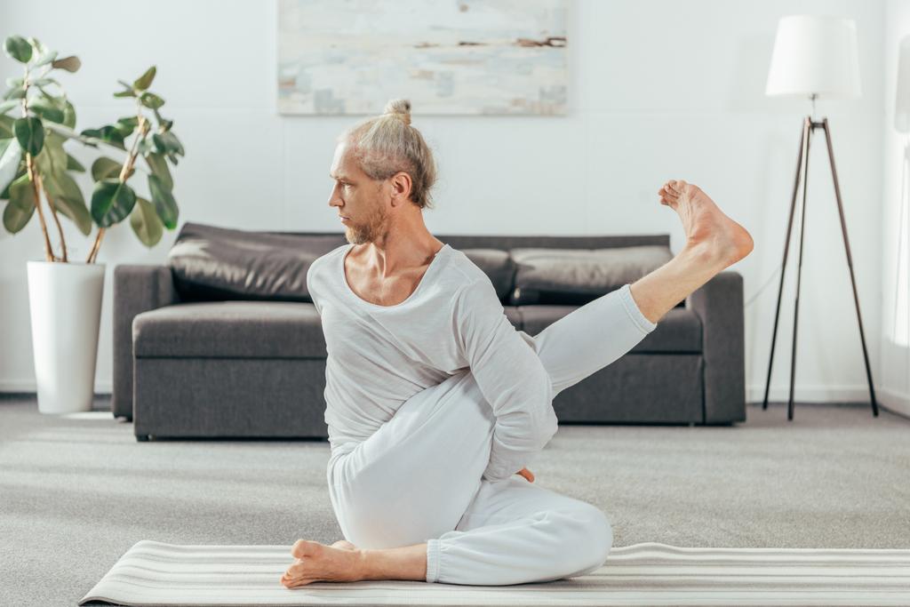 Koncentrovaná dospělý člověk cvičí jógu na mat doma - Fotografie, Obrázek