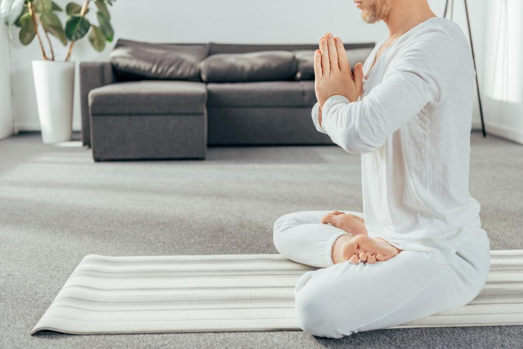vágott lövés a felnőtt ember meditál a lótusz helyzet a jóga mat otthon    - Fotó, kép