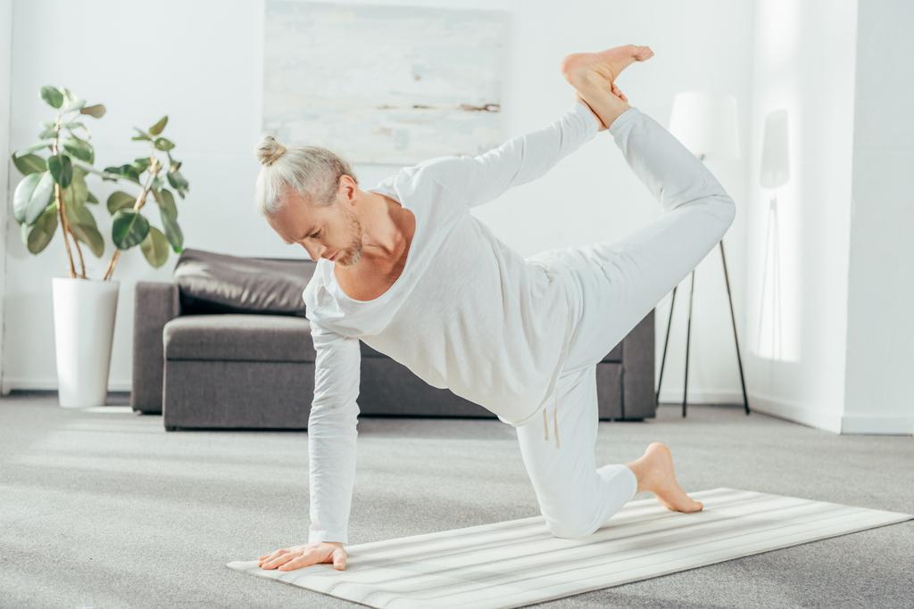 vista completa del hombre adulto descalzo practicando yoga en casa
 - Foto, Imagen