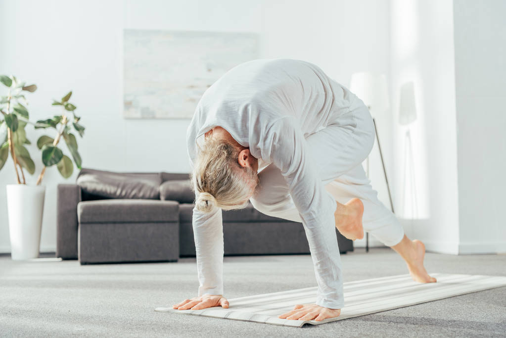 Barfuß erwachsener Mann macht Longe Yoga-Übung auf Matte zu Hause - Foto, Bild