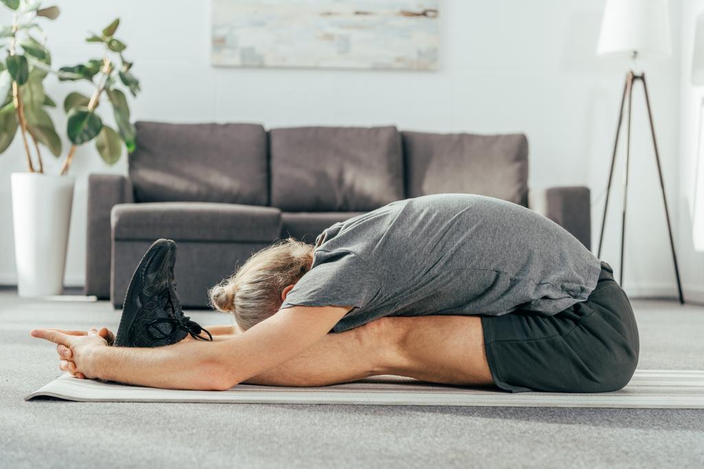 egzersiz ve evde yoga mat germe sportif yetişkin adam yan görünüm - Fotoğraf, Görsel