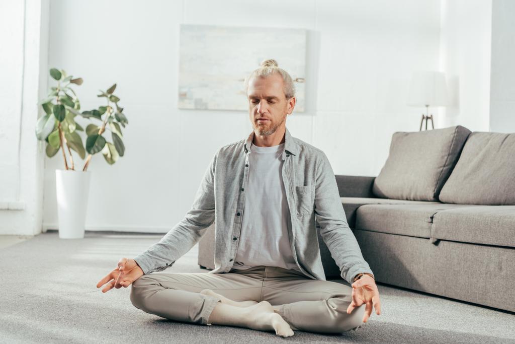 sporty adult man meditating in lotus position at home - Photo, Image