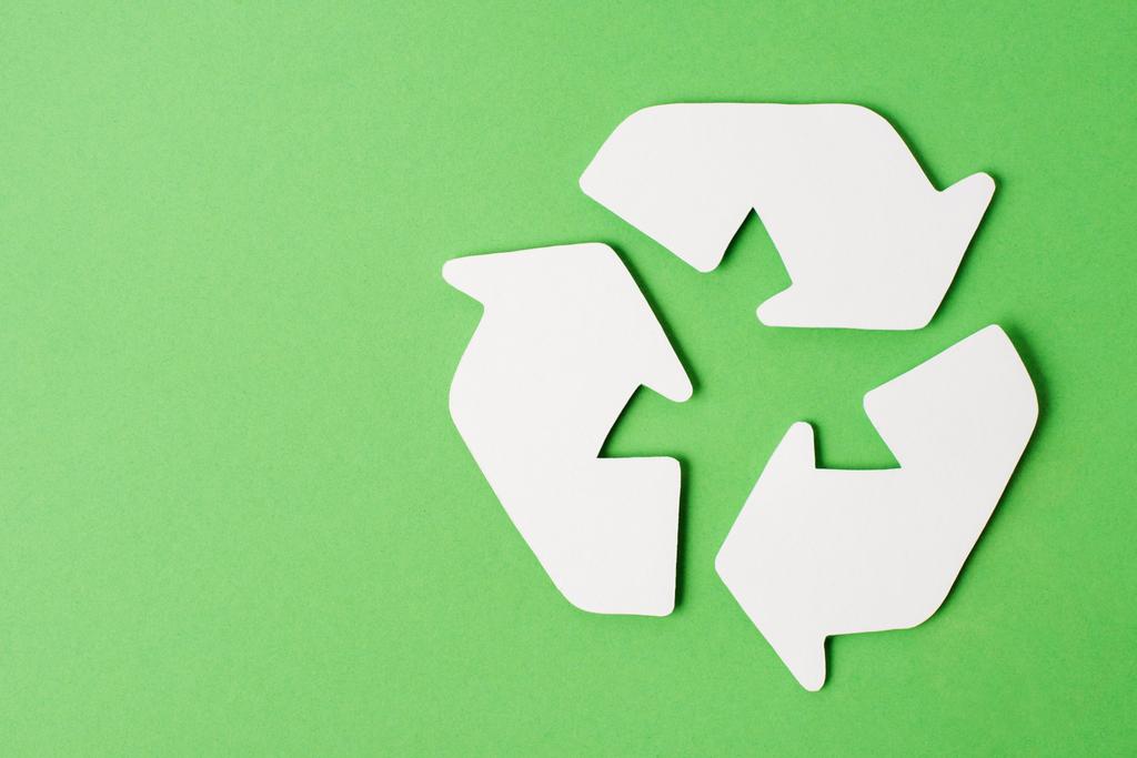 Vista superior do sinal de reciclagem branco no fundo verde
 - Foto, Imagem