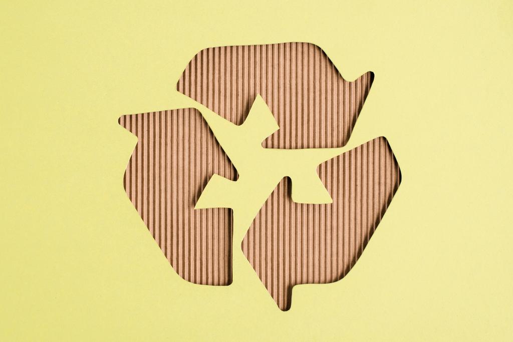 Vista superior do sinal de reciclagem de papelão no fundo amarelo
 - Foto, Imagem