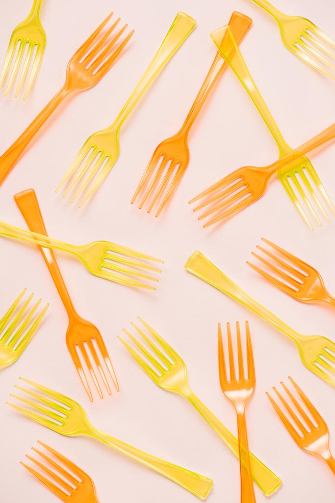 Top view of colorful orange and yellow plastic forks on pink background - Photo, Image