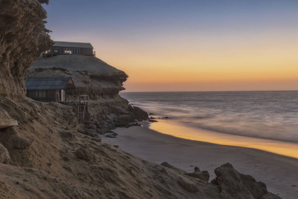 Beautiful sunset on the coast of the Namibe Desert with canyons and wooden houses. Angola. Africa. - Photo, Image