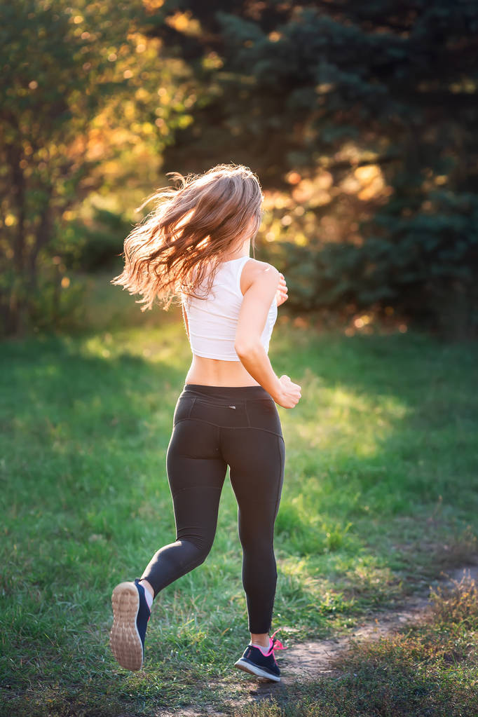 Красива молода спортивна жінка біжить в парку під час заходу сонця
 - Фото, зображення