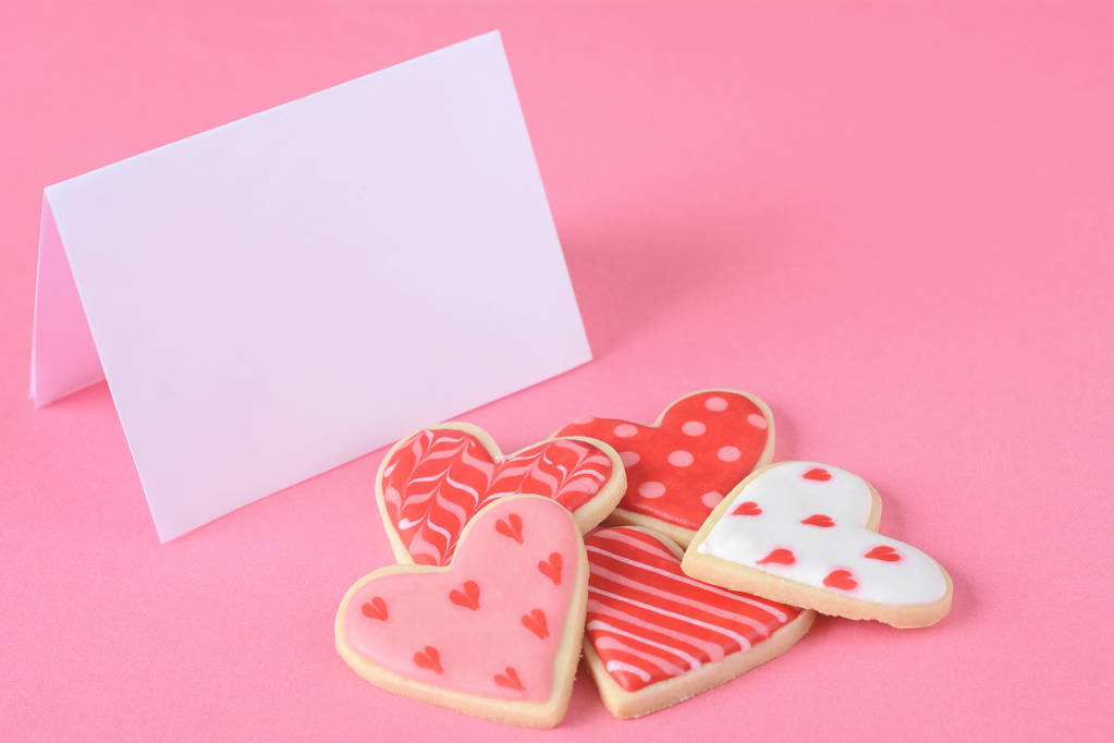 Primer plano de las galletas del día de San Valentín con tarjeta de felicitación sobre fondo rosa. Espacio de copia
 - Foto, imagen