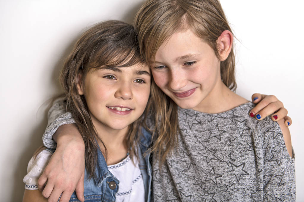 zwei glückliche Kinder Schwester steht an leeren grauen Wand und umarmt - Foto, Bild