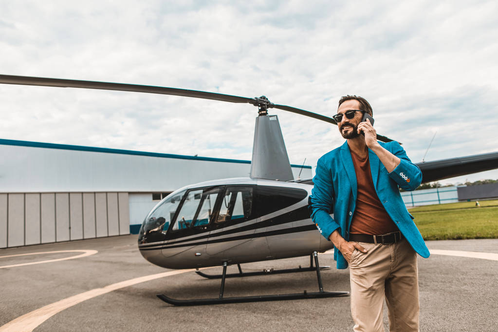 Привабливим чоловіком в барвисті одягу, стоячи біля вертоліт з смартфон - Фото, зображення