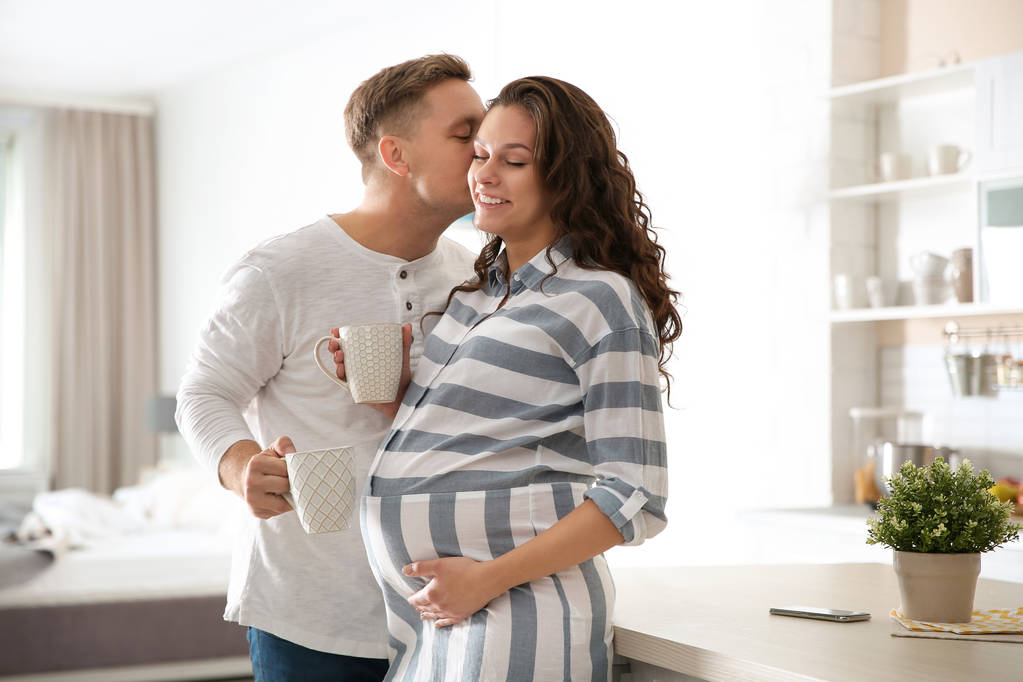 Těhotná žena se svým manželem v kuchyni. Mladá rodina - Fotografie, Obrázek