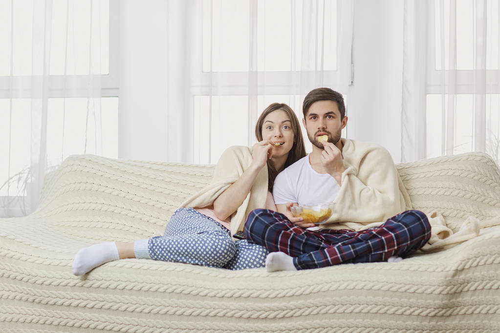 Un jeune couple assis sur le canapé regardant une télévision intéressante
 . - Photo, image