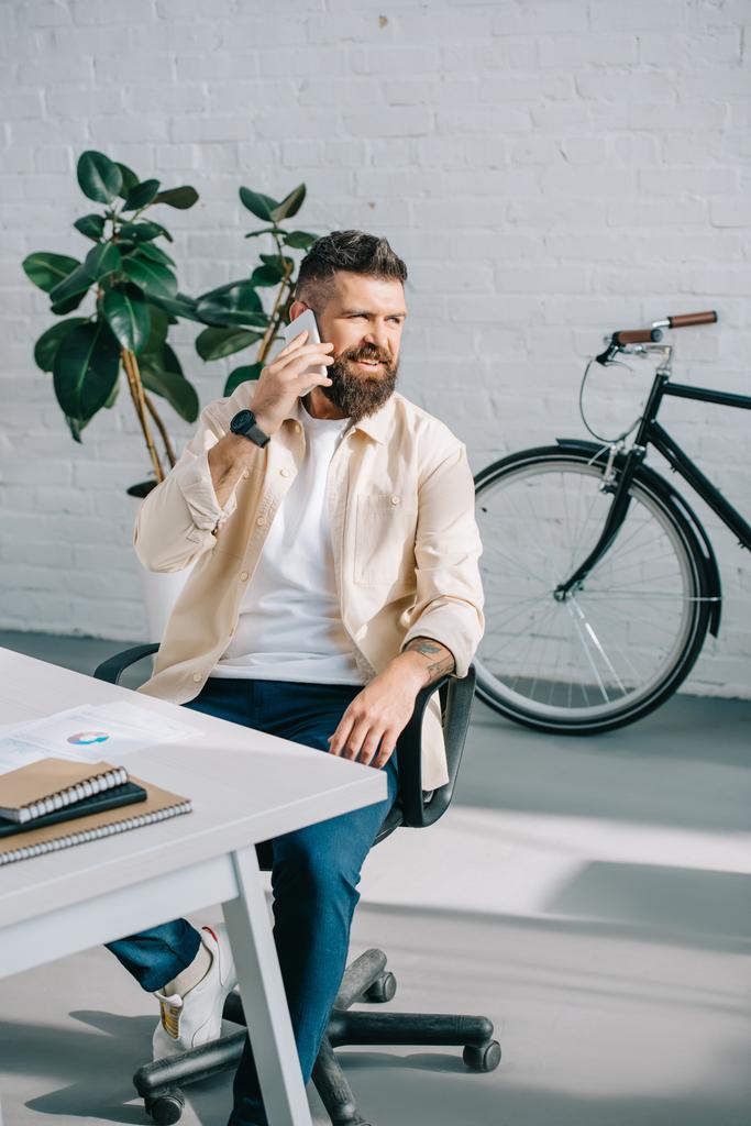Office sandalyede oturan ve smartphone üzerinde konuşurken sakallı işadamı  - Fotoğraf, Görsel