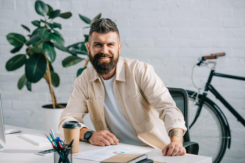 Bearded businessman sitting in modern office and smiling at camera - Photo, Image