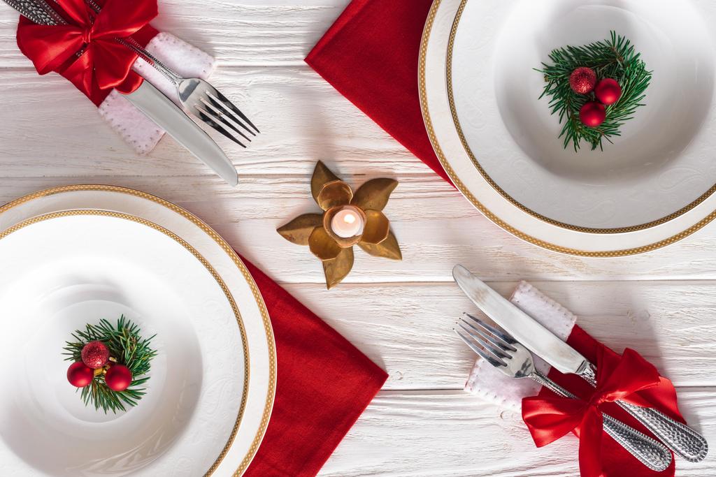 koholla näkymä tarjoillaan pöydän kynttilä, haarukat, veitset ja lautaset ikivihreä oksat koristeltu joulupallot
  - Valokuva, kuva