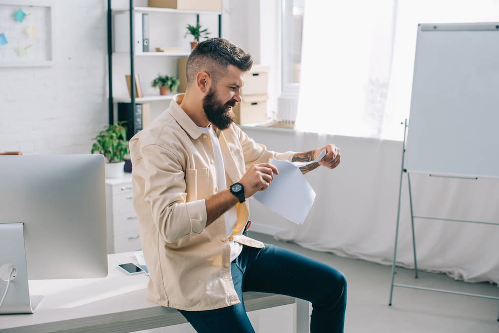 Angry casual businessman tearing papers in modern office  - Photo, Image
