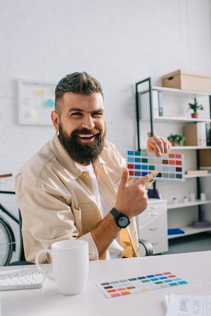 Handsome designer pointing at color palette in modern office - Photo, Image