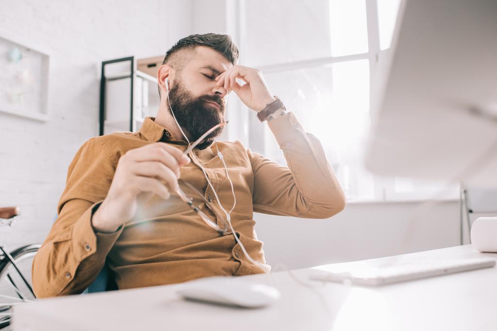стресова бородатий дорослий бізнесмен в навушниках, що працюють за столом в офісі
 - Фото, зображення