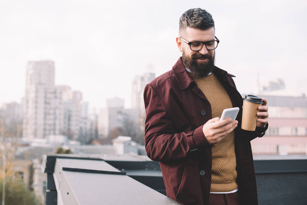 hombre adulto con estilo en vasos de café para llevar y el uso de teléfono inteligente en la azotea
 - Foto, imagen