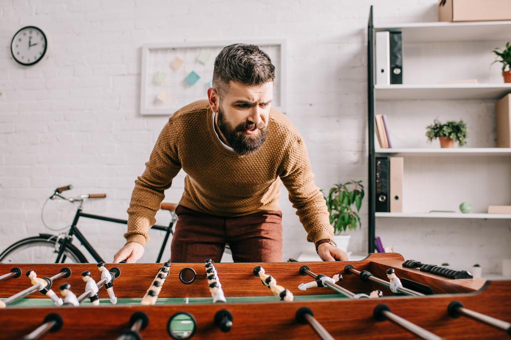 bearded adult man playing table football game at home - Photo, Image