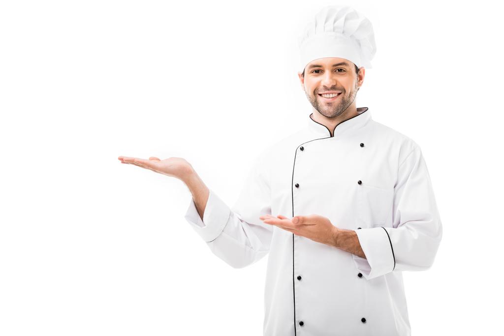 onnellinen nuori kokki osoittaa tyhjään tilaan ja katselee kameraa, joka on eristetty valkoisella
 - Valokuva, kuva