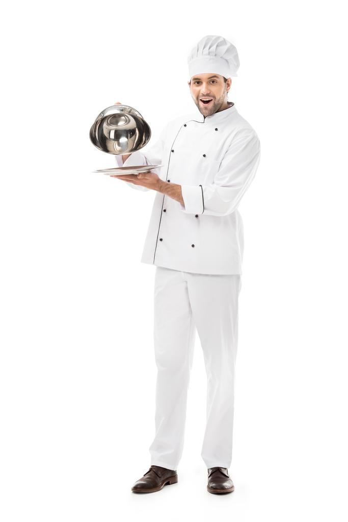 emotional young chef taking of serving dome from plate isolated on white - Photo, Image