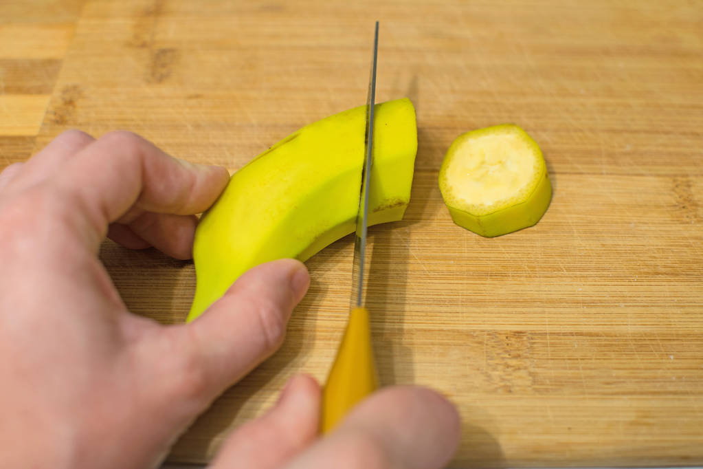Mulher cortando uma banana madura em uma tábua de madeira. Fatias de banana doce suculentas
. - Foto, Imagem