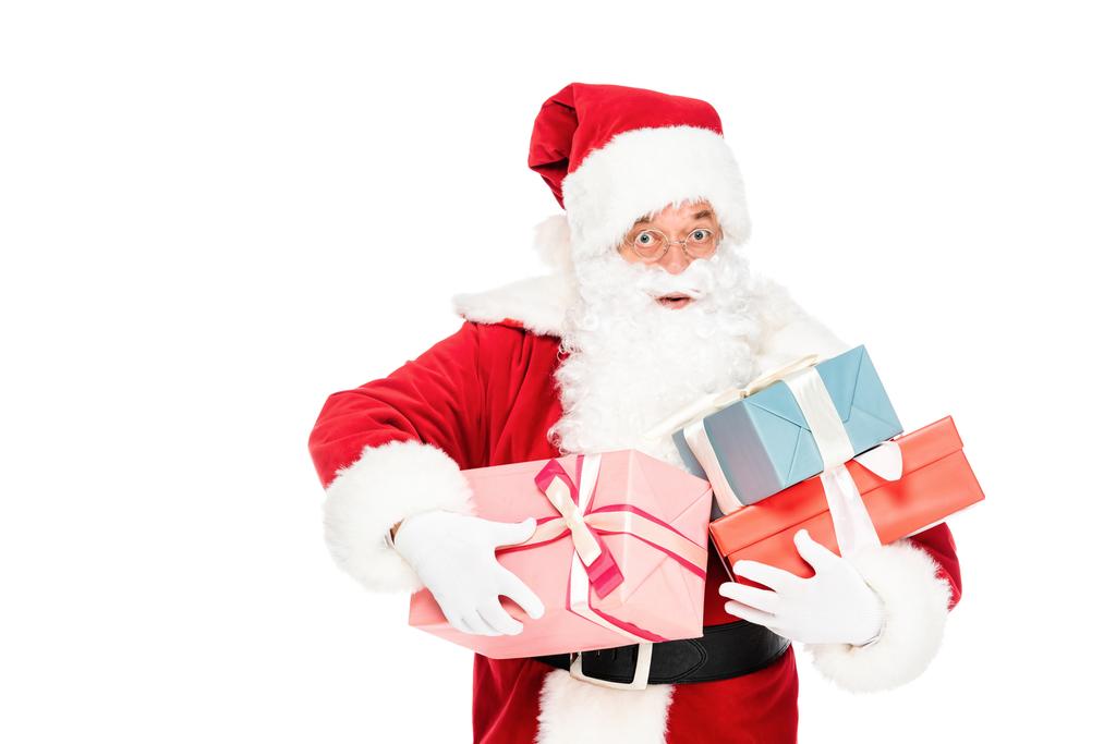 Санта Клаус тримає купу подарункових коробок і дивиться на камеру з шокованим виразом ізольовано на білому
 - Фото, зображення