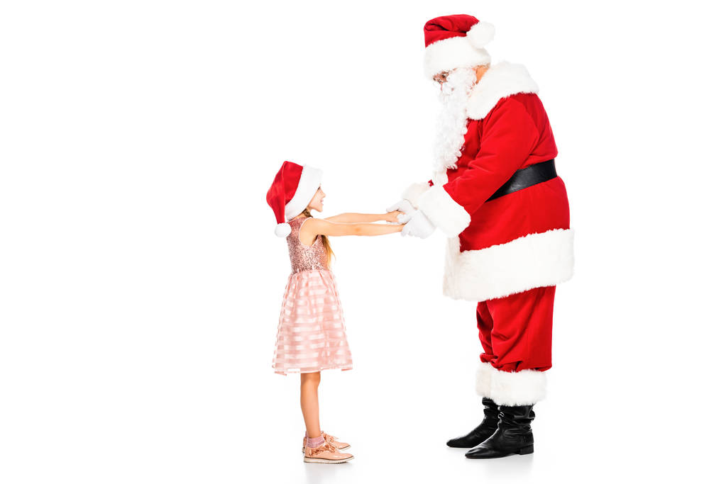 boční pohled na santa claus a malé dítě drží za ruce, izolované na bílém - Fotografie, Obrázek
