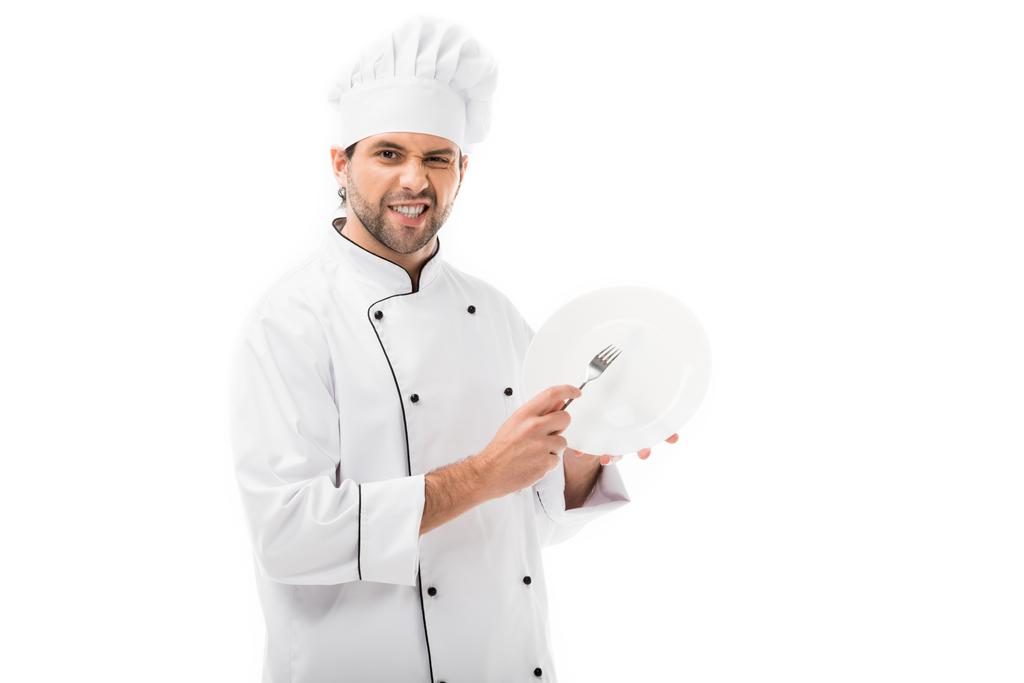 young chef scratching plate with fork isolated on white - Photo, Image