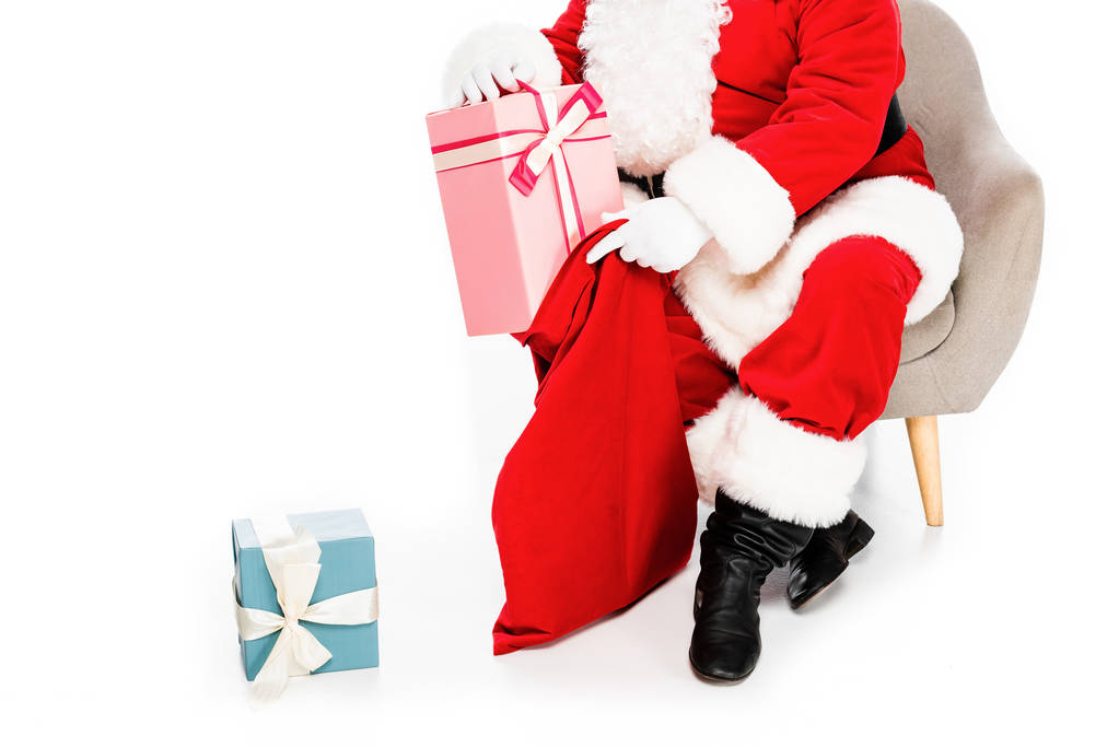ritagliato colpo di Babbo Natale seduto in poltrona con regali e borsa isolata su bianco
 - Foto, immagini