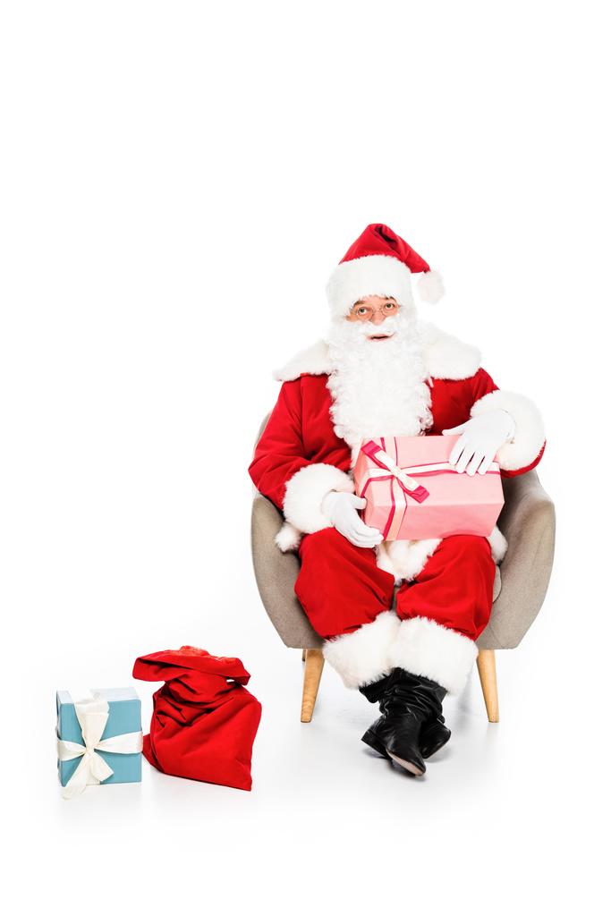 santa claus sitting in armchair with various gift boxes isolated on white - Photo, Image