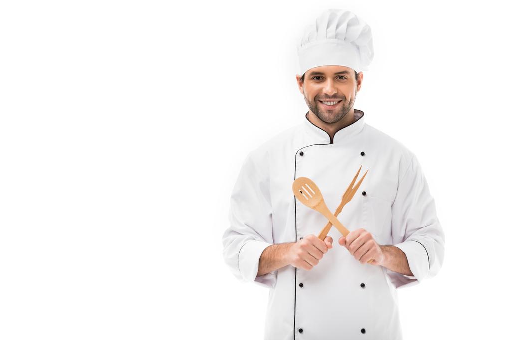 щасливий молодий шеф-кухар тримає дерев'яне кухонне начиння і дивиться на камеру ізольовано на білому
 - Фото, зображення