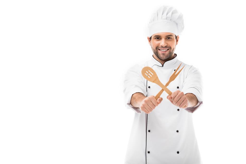 улыбающийся молодой шеф-повар, держащий деревянную кухонную утварь и смотрящий на камеру, изолированную на белом
 - Фото, изображение