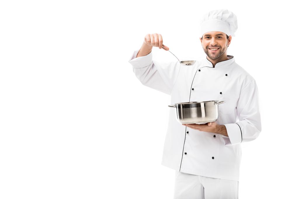 lachende jonge chef-kok met het koken van de pot en pollepel geïsoleerd op wit - Foto, afbeelding
