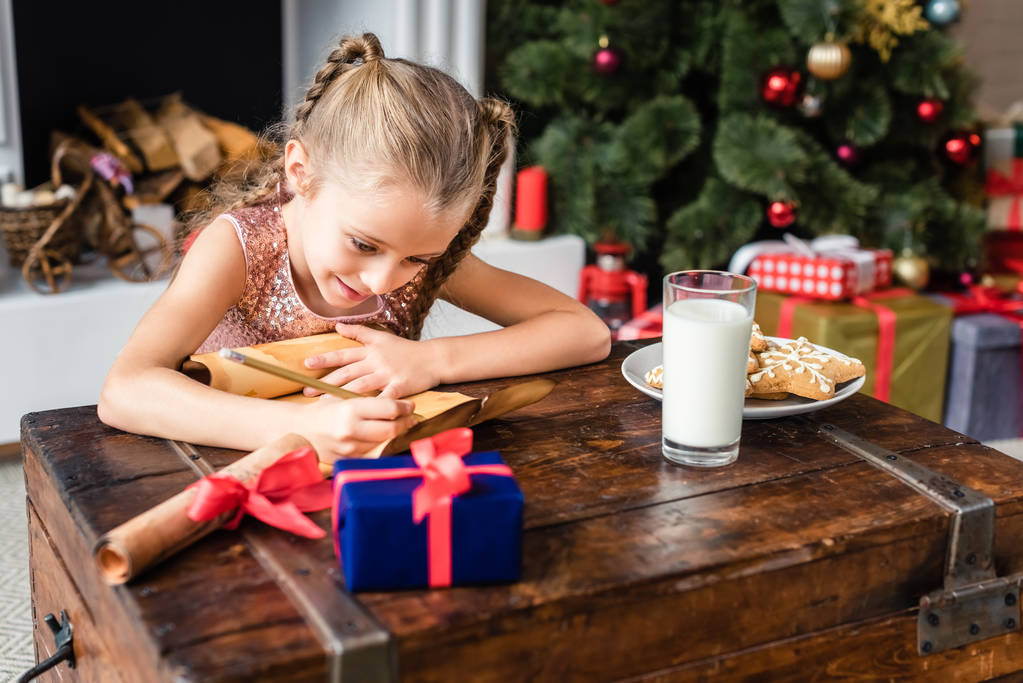 cute smiling kid writing wishlist on parchment at christmas time - Photo, Image
