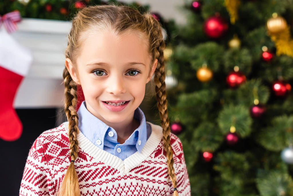 Porträt eines entzückenden glücklichen kleinen Kindes, das zur Weihnachtszeit in die Kamera lächelt  - Foto, Bild
