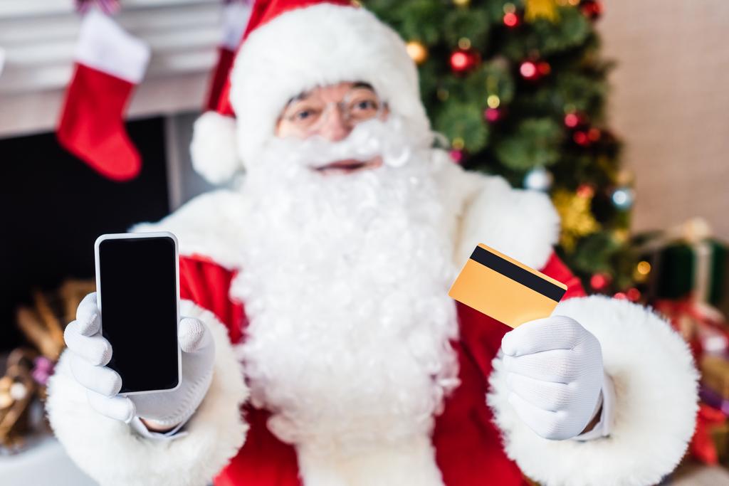 クレジット カードと空白の画面で示すスマート フォン保持サンタ クロース - 写真・画像
