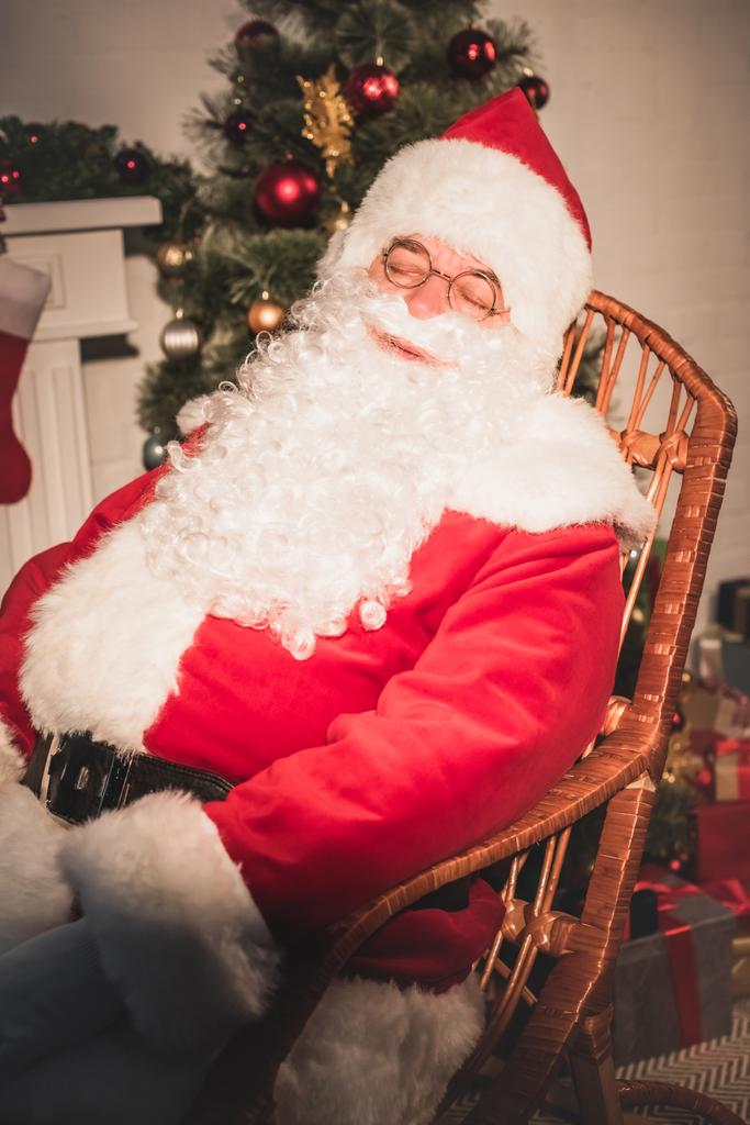 Santa claus spí v houpacím křesle u krbu a vánoční stromeček - Fotografie, Obrázek