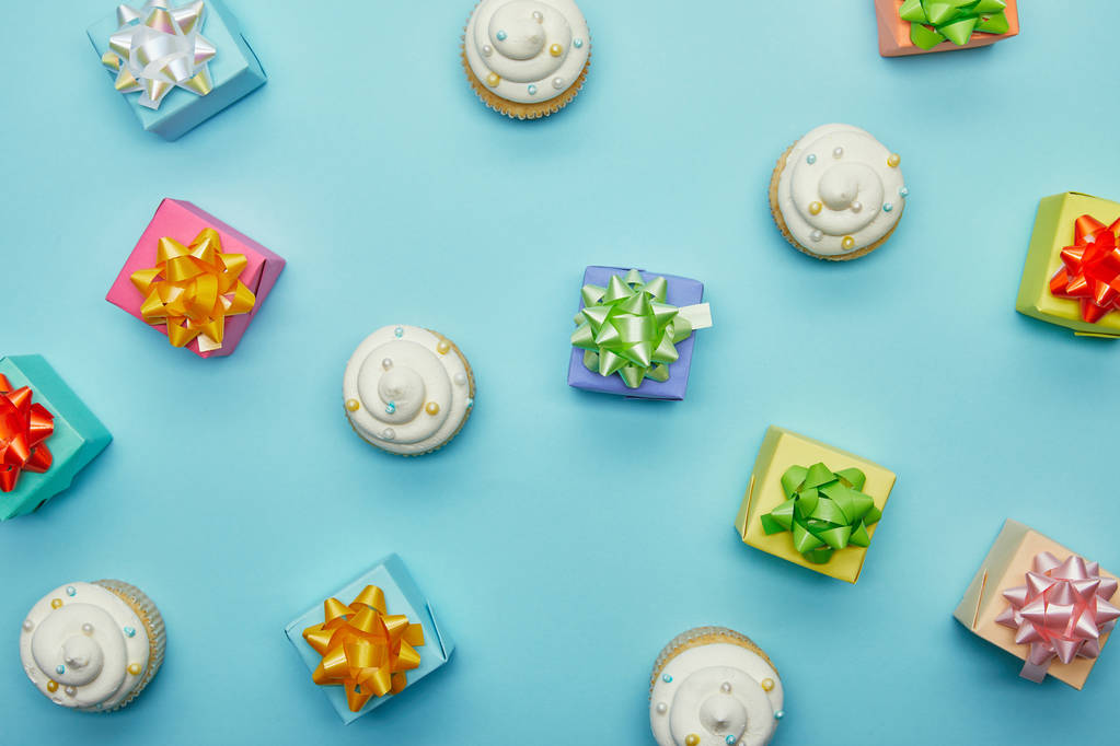 Vista dall'alto di deliziosi cupcake e regali su sfondo blu
 - Foto, immagini