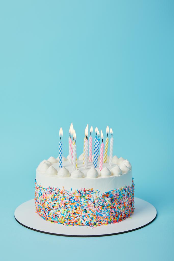 leckere Geburtstagstorte mit brennenden Kerzen auf blauem Hintergrund - Foto, Bild