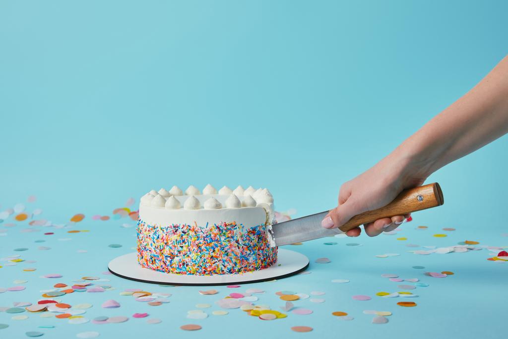 Cropped view of woman cutting delicious cake on blue background - Photo, Image