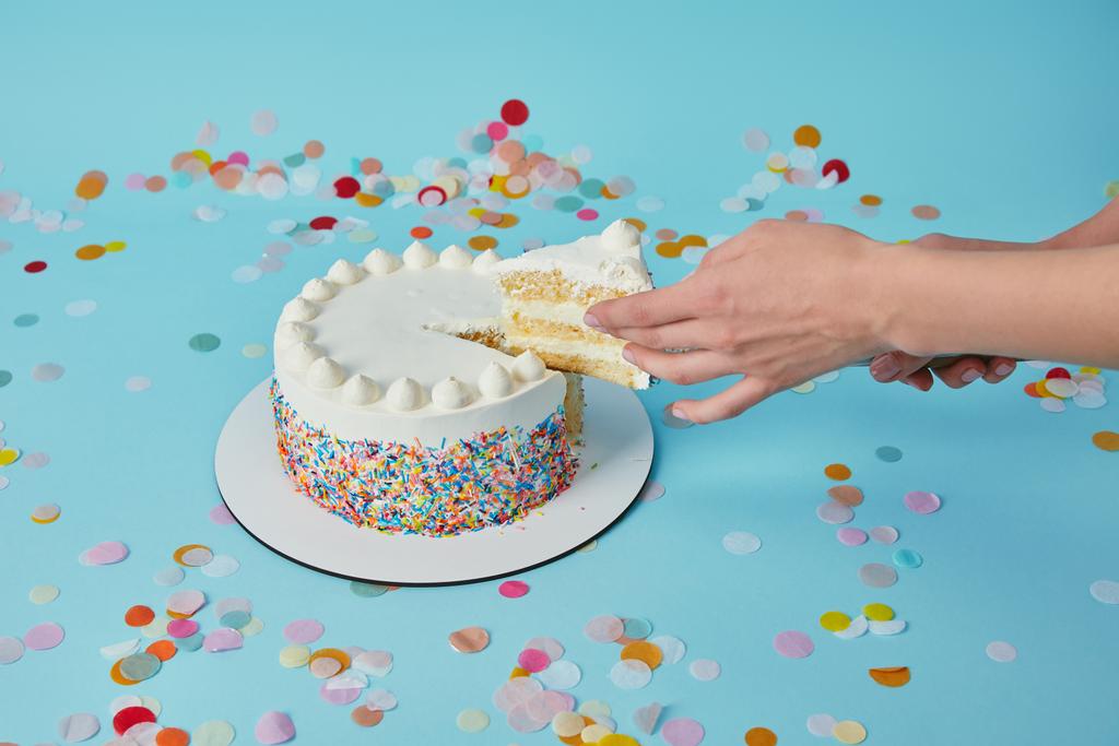 Partial view of woman taking piece of delicious cake on blue background - Photo, Image