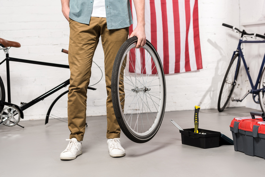 imagen recortada del hombre sosteniendo la rueda de bicicleta en la mano
  - Foto, Imagen