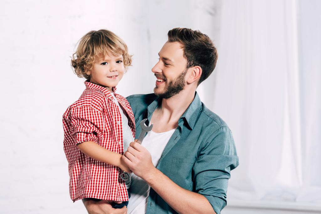 Porträt eines glücklichen Vaters mit kleinem Sohn in der Hand  - Foto, Bild